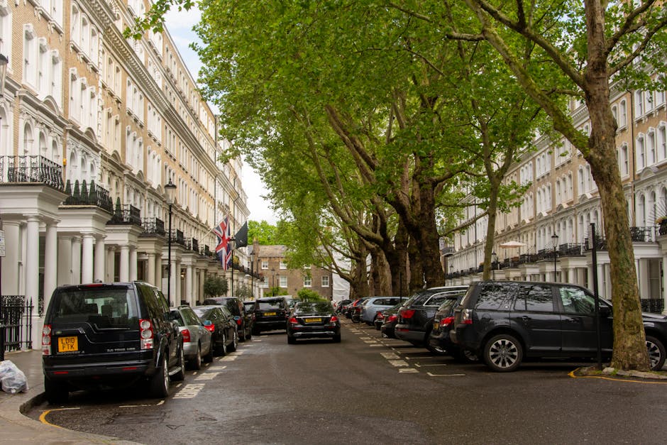 A rectangular white street sign mounted on a stone wall in Westminster, London, displaying 'PARK LANE W1' in bold black and red letters, with 'CITY OF WESTMINSTER' written beneath in smaller red text.